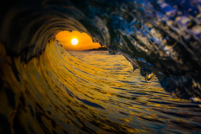 Looking out from inside a breaking wave toward the sun setting over the sea